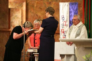Sister Beth Wright kisses the Bible after professing her lifelong commitment as a Sister of Providence of Saint Mary-of-the-Woods during a liturgy on June 30. General Officer Sister Dawn Tomaszewski holds the Bible as General Superior Sister Denise Wilkinson and Father Daniel Hopcus look on.