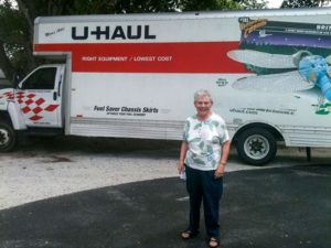 Sister Cathy Buster stands aside a truck used to move families to Casa San Juan Bosco