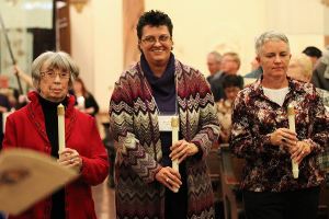 Jean Smith, Sarah Wilson and Traci Tucker carry candles during the entrance procession for their commitment ceremony as Providence Associates.