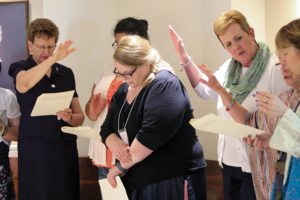 Providence Associate Kaitlyn Willy, who is currently in graduate school in Texas, renewed her commitment as a Providence Associate while at Saint Mary-of-the-Woods for Chapter. Here Sister Dawn Tomaszewski at left and Providence Associate Debbie Dillow at right, join with other sisters and associates to pray a blessing over Kaitlyn during her recommitment.