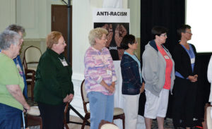 Sisters and associates choose justice issues they would like to focus on by moving to its sign in the room. From left, Sisters Mary Beth Klingel, Lucy Nolan, My Huong Pham, Carole Kimes and Providence Associate Maria Price show support for work to promote anti-racism.