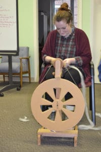 Intern Isabelle McCurdy tries her hand at spinning fiber.