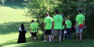 A group of people in matching t-shirts following a woman dressed as Mother Theodore