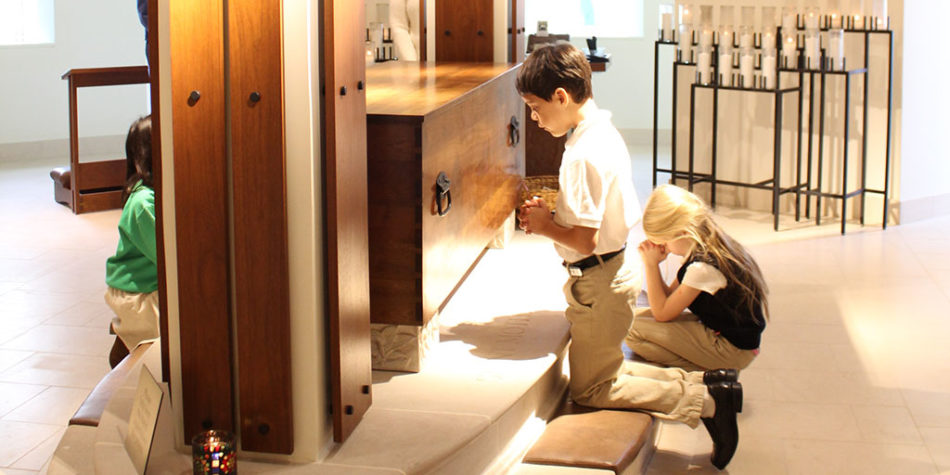 a child kneeling in front of the wooden casket of Saint Mother Theodore Guerin