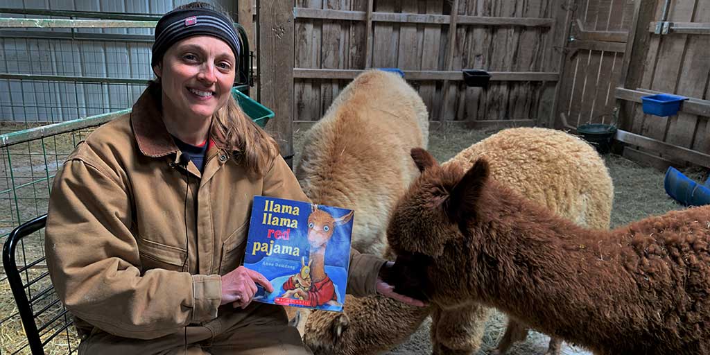 Farmer Tara from White Violet Center reads to the alpacas