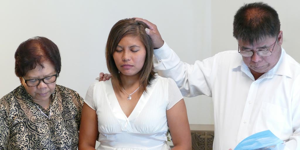 Jessica's parent lay their hands on her head in blessing
