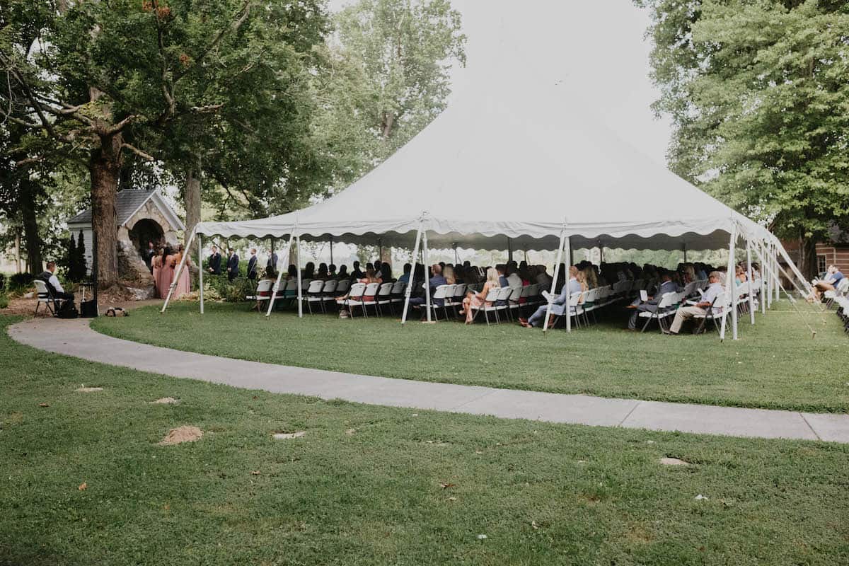 An elegant white tent on the grounds, under which guests sit