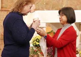 Sister Norene Wu (right) offering communion to Sisters of Providence employee Diane Weidenbenner, who works in the Congregation Mission Advancement Department.