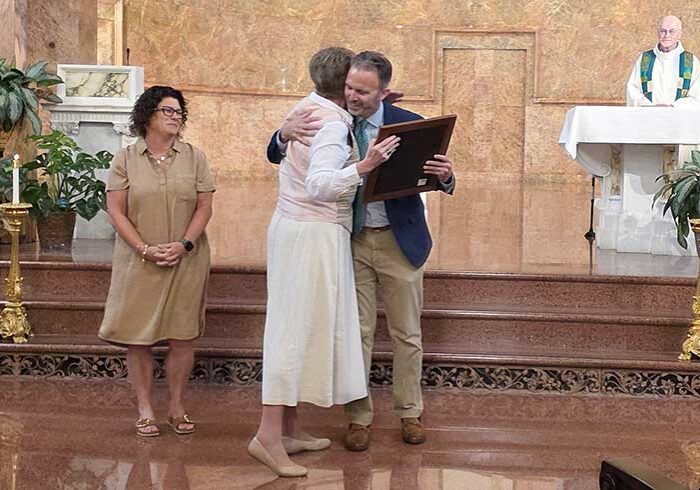 General Superior Sister Dawn Tomaszewski embracing Greg VanSlambrook after presenting him with plaque containing the Congregation's Purpose, Mission and Vision Statements as Beth Desalvo (left) and Father Terry Johnson look on.