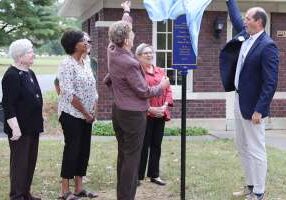 (From left) Sister Jan Craven, Saint Mary-of-the-Woods College (SMWC) representative Dee Reed, former SMWC representative Susan Dolle (behind Reed) and Sister Paula Damiano (back) watch as Sister Dawn Tomaszewski and SMWC Interim President Brennan Randolph unveil the sign marker.