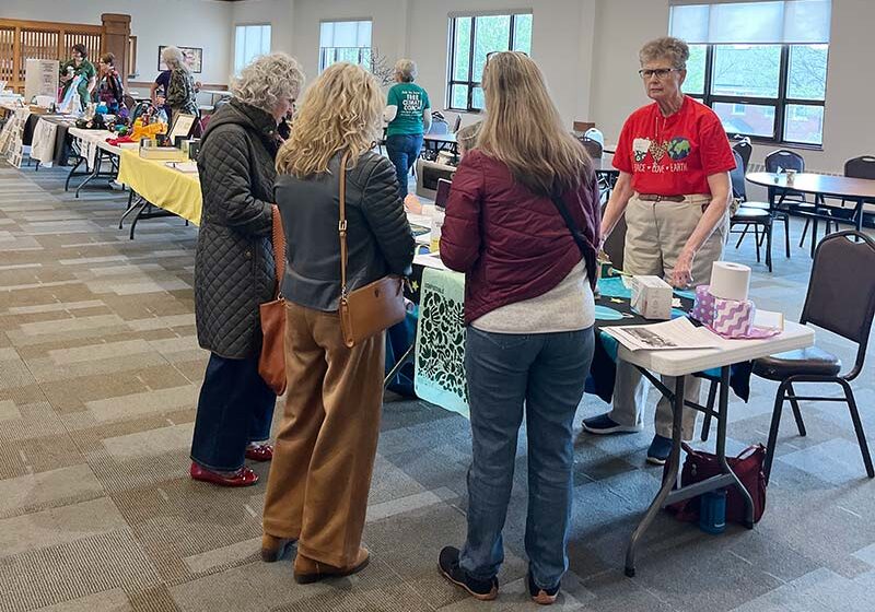 Sister Mary Tomlinson, SP, (in red shirt) discussing the Climate Action Now (CAN) app with others at the Sustainability Fair.