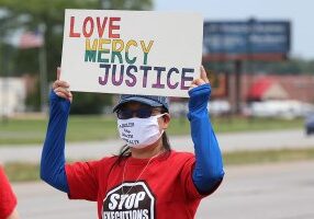 Sister Teresa Kang holds a love, mercy, justice sign during the anti-death penalty protest at US 41 and Springhill in 
Terre Haute on Wednesday.
