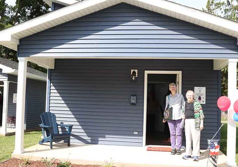 Sister Mary Montgomery (left) with Sister Donna Butler in front of one of the homes at Veterans Village in Terre Haute.
