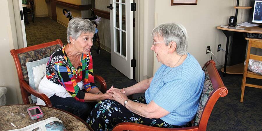 Deanna Ruston spends time visiting and praying with Sister Suzanne Buthod during a volunteer week at the Woods. 