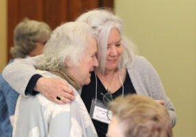 Providence Associates Sheila Donis and Regina Hartman greet one another with a hug.