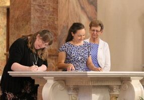 Sisters Arrianne and Tracey sign as Sister Dawn looks on.