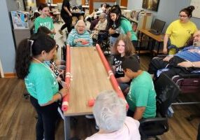 Several teen volunteers enjoy playing a game with Sister Dorothy Larson.